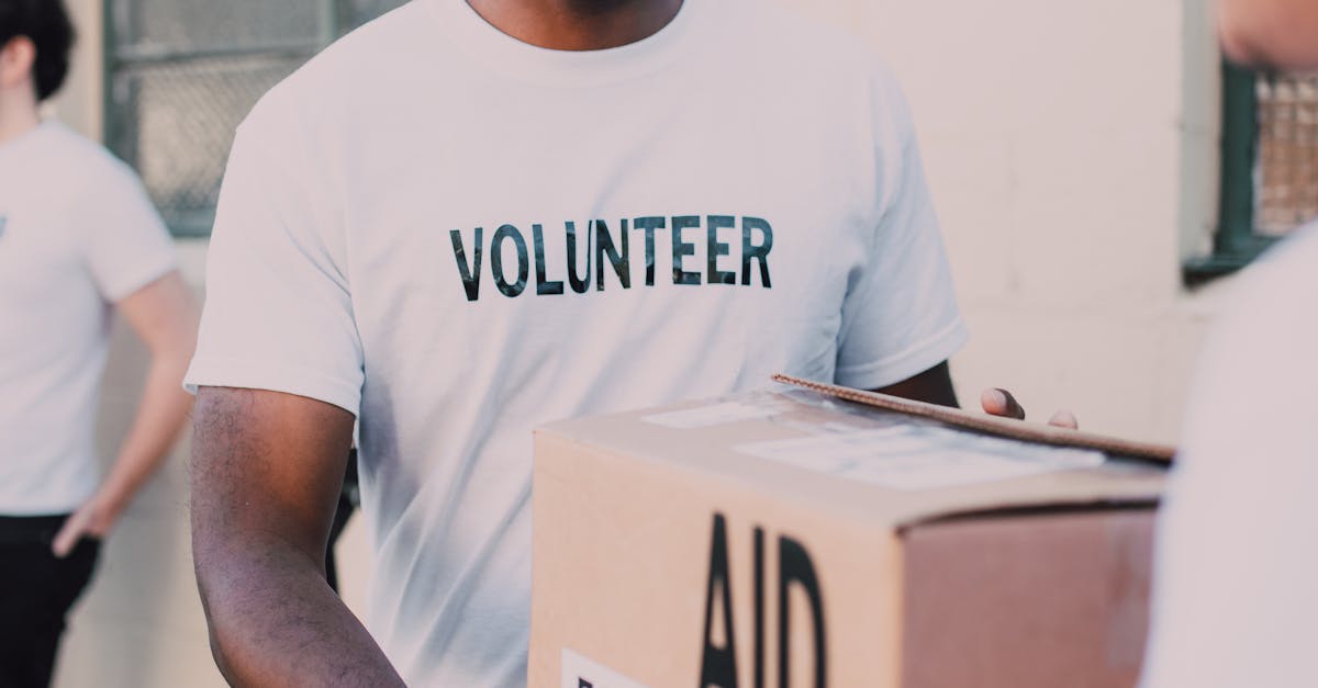 Man in White Crew Neck T-shirt Holding Brown Box